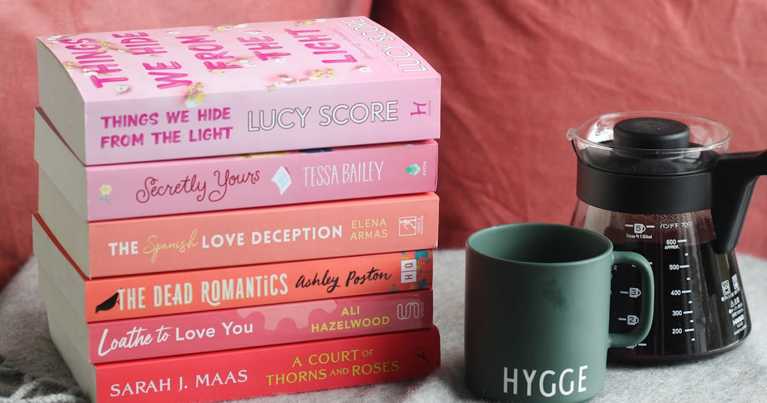 Stack of pink romance novels with coffee — BookTok books